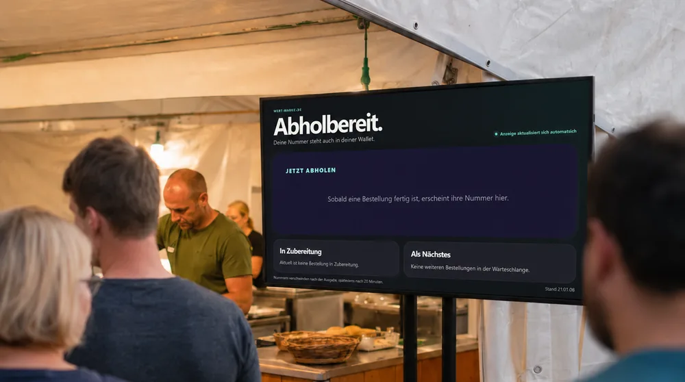 Gäste vor einem Bildschirm mit den fertigen Abholnummern