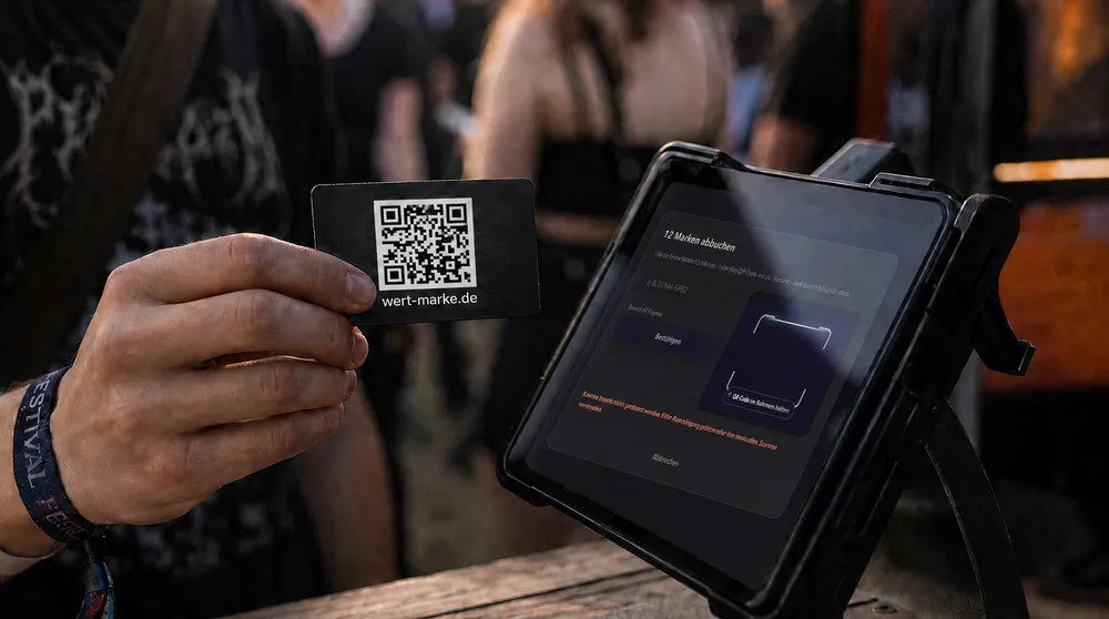 Hand hält eine Wertmarken-Karte mit QR-Code vor ein Kassengerät